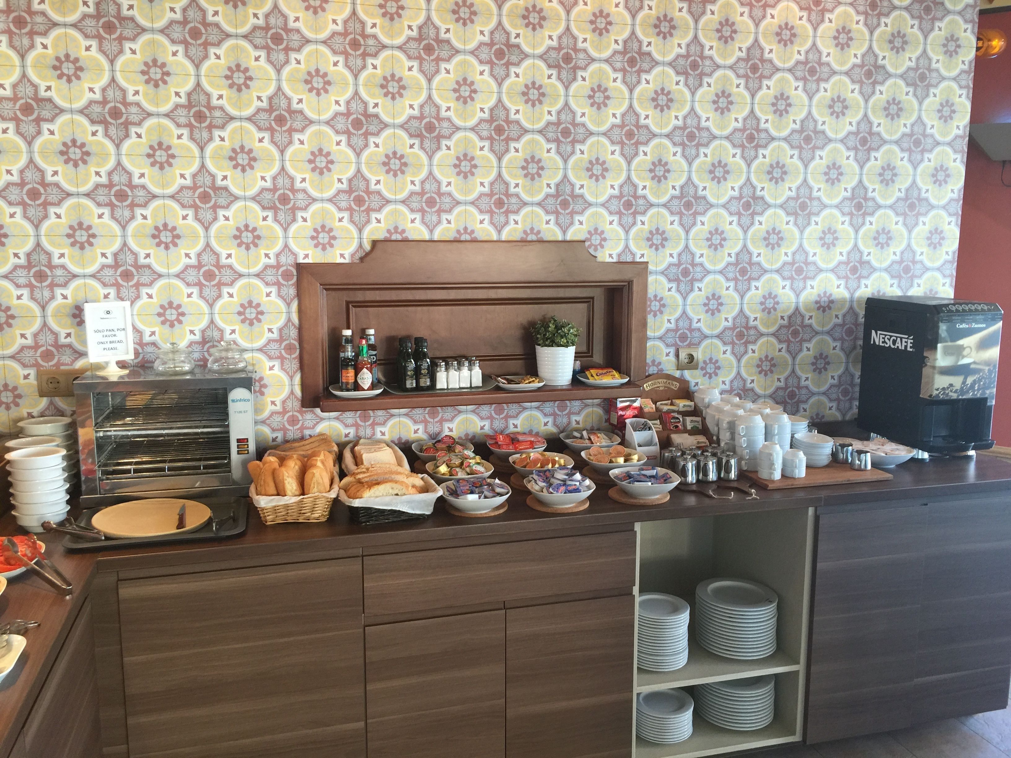 A breakfast buffet with bread, pastries, and condiments.
