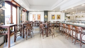 Un restaurante espacioso con techos altos, taburetes de madera y una larga barra con vitrina de vidrio.