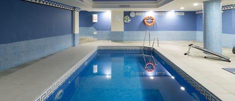 An indoor swimming pool with blue tiled walls and a clear pool area.