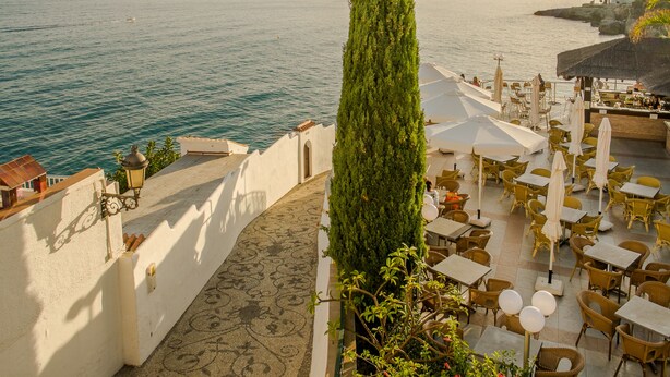 Una terraza al aire libre con mesas y sillas, con vistas al mar.