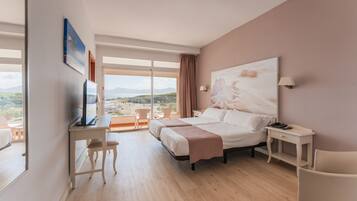 Habitación de hotel con cama, escritorio, silla, televisión y un ventanal con vistas al paisaje.