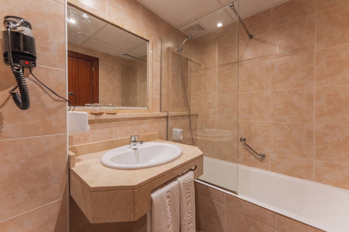 Een badkamer met een wastafel, spiegel en douche.