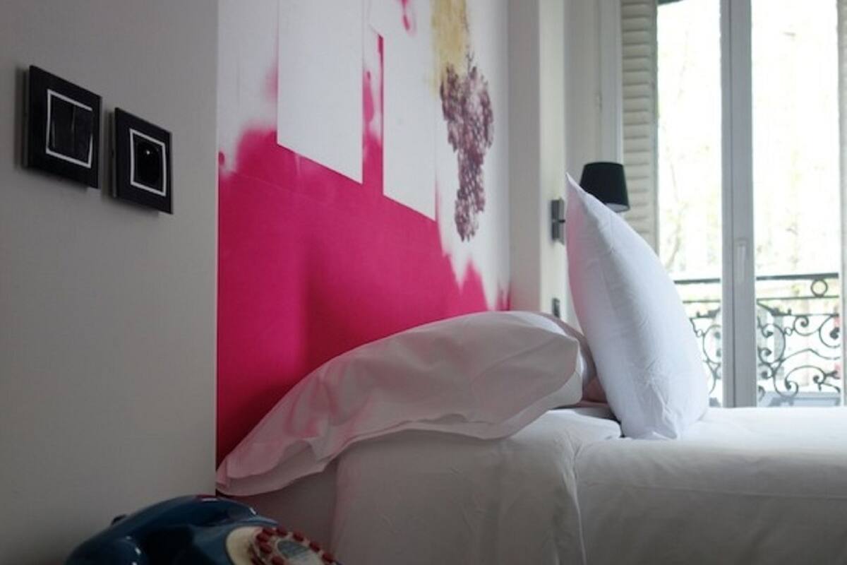 Une chambre d’hôtel avec un lit, un téléphone et une fenêtre donnant sur un paysage agréable.