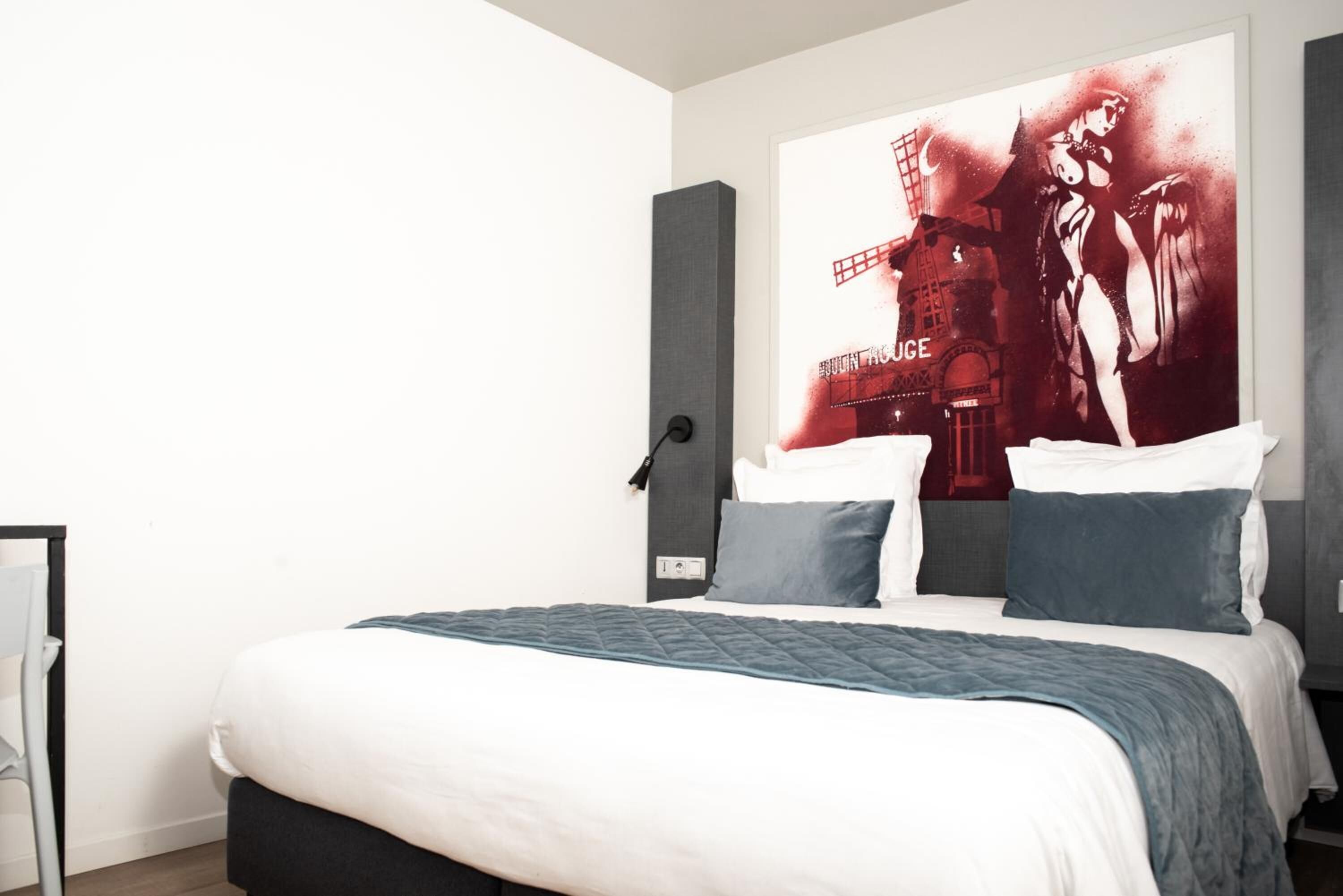 A modern bedroom with a large bed, a headboard, and a wall-mounted artwork.
