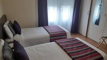 Una habitación de hotel con dos camas, una ventana con cortinas y un cuadro en la pared.
