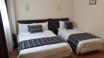 Een hotelkamer met twee bedden, elk met een streepjesbeddeken en kussens.