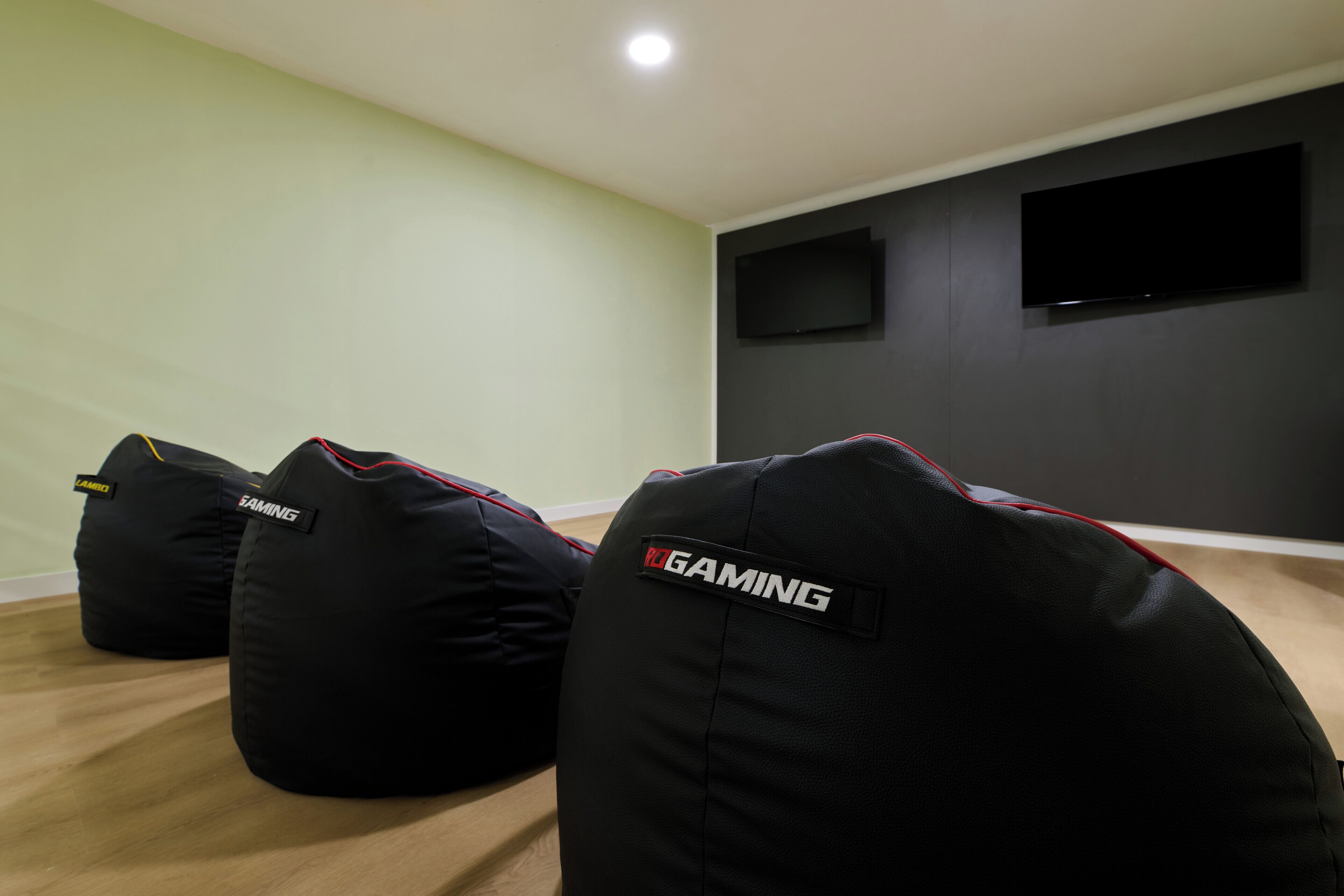 Sillones de felpa con la etiqueta 'RGAMING' en una habitación con suelo de madera y un televisor de pantalla plana montado en la pared.