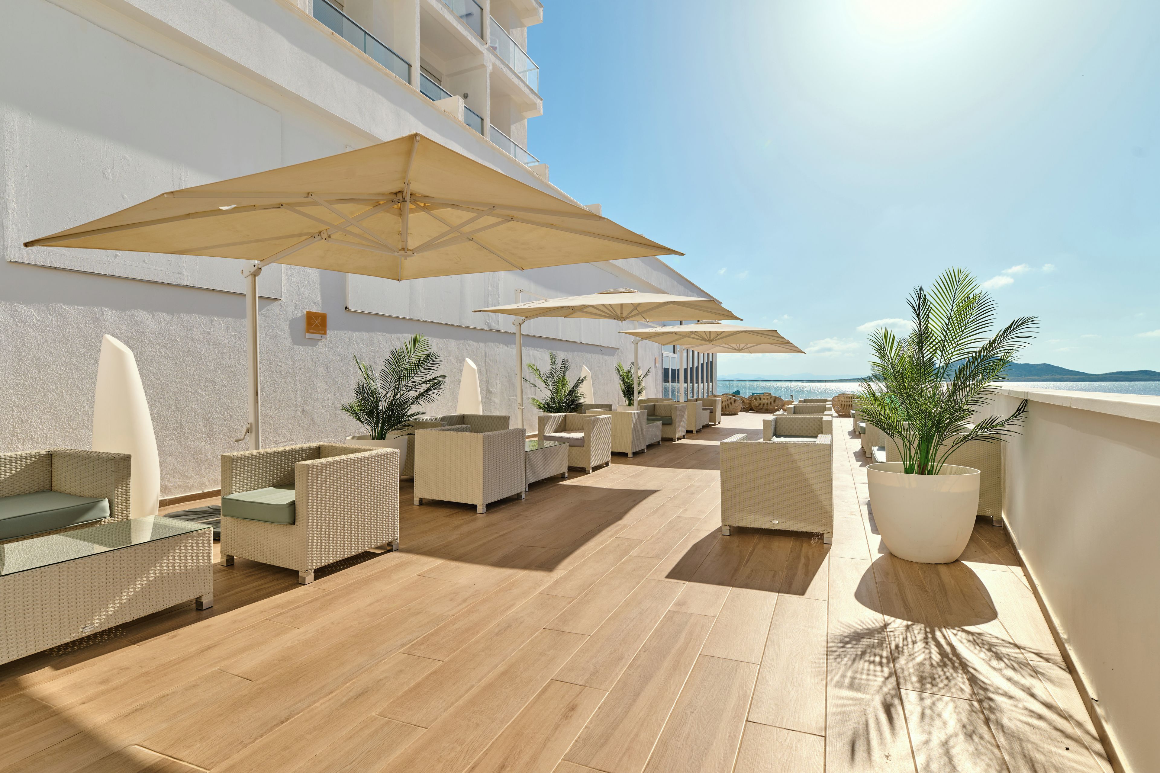 A rooftop terrace with outdoor seating, umbrellas, and potted plants.