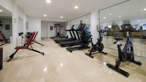 A gym with exercise equipment, a mirror, and a clean floor. - Aluasun Doblemar (San Javier)