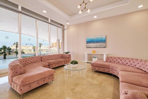 A modern living room with a sectional sofa, a glass coffee table, and a painting on the wall.