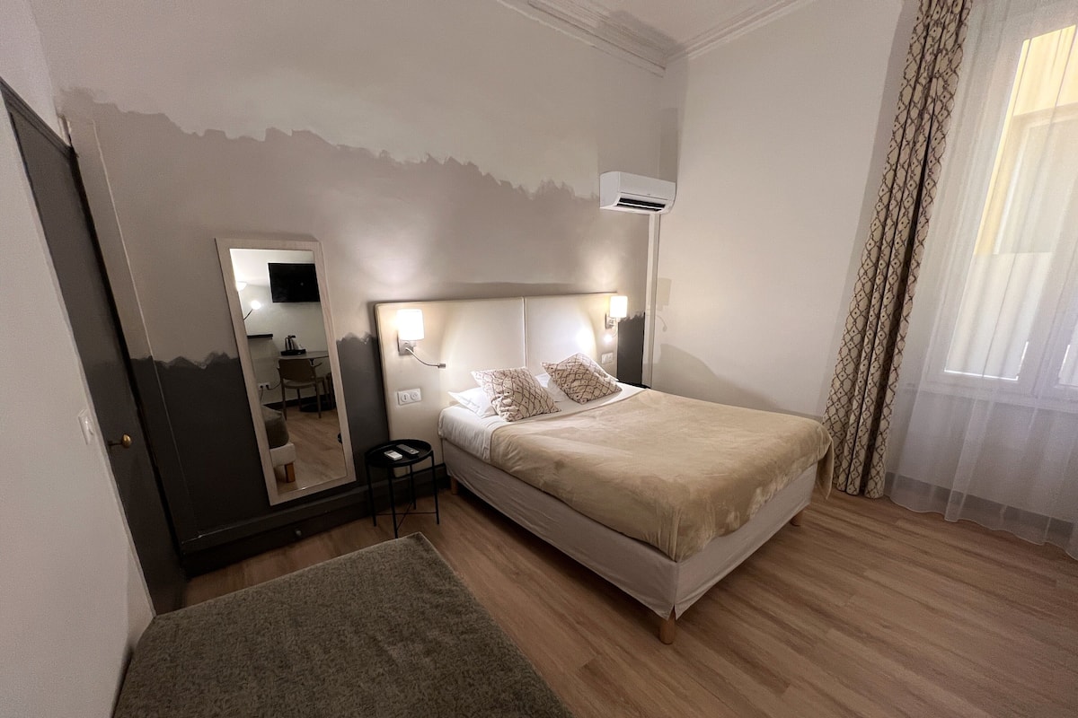 A hotel room with a bed, bedside table, mirror, and a small round table.