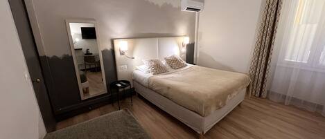 A hotel room with a bed, bedside table, mirror, and a small round table.