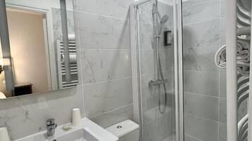 A modern bathroom with a glass-enclosed shower, a white sink, and a toilet.
