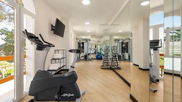 Ein modernes Fitnessstudio mit Laufbändern, Kraftgeräten und einer Spiegelwand.