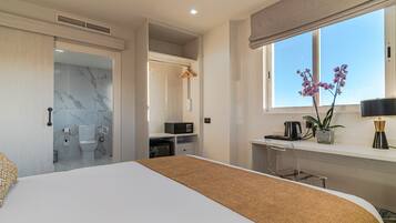 Un dormitorio moderno con una cama grande, un baño con paredes de mármol, un escritorio con lámpara y una ventana con vistas.