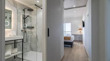 A modern bathroom with a glass-enclosed shower, marble walls, and a white sink.
