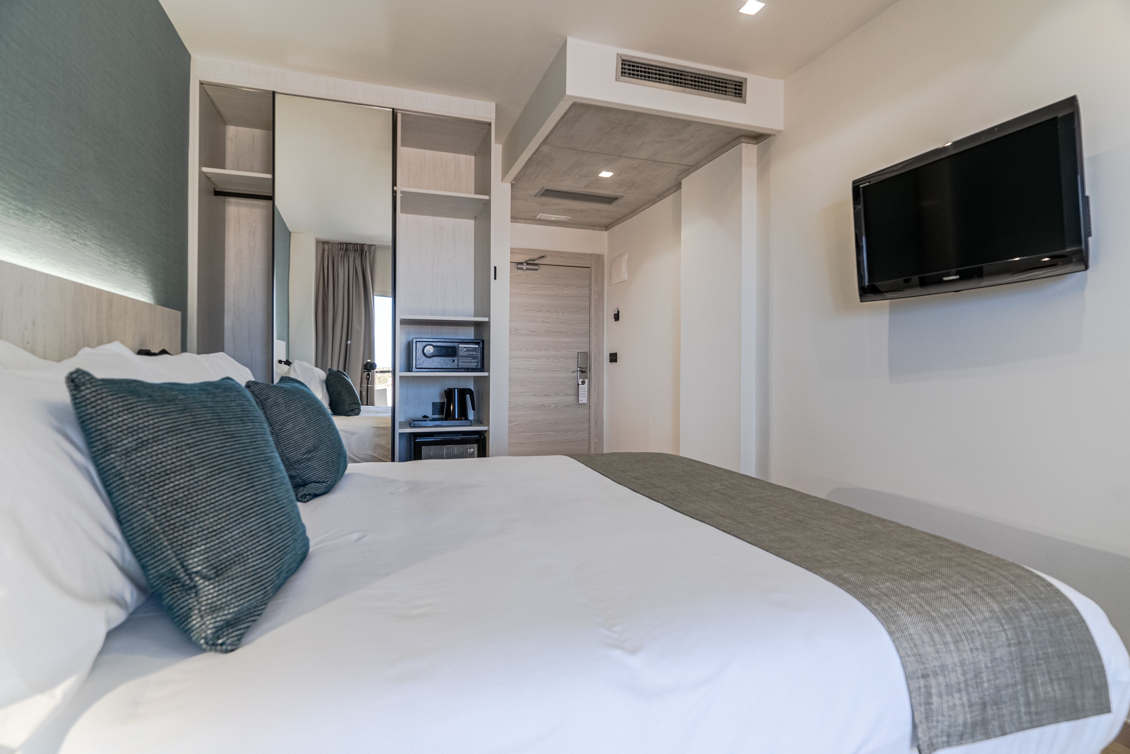 Een hotelkamer met een groot bed, een aan de muur bevestigde televisie en een inloopkast.