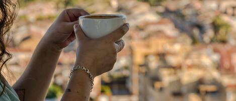 Una persona sosteniendo una taza, con una vista costera al fondo.