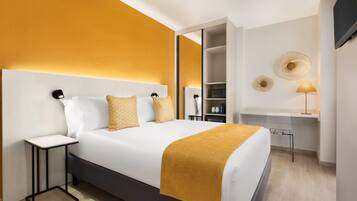 A modern hotel room with a large bed, bedside tables, a desk, and a TV mounted on the wall.