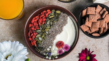 Un tazón de yogur cubierto de semillas, nueces y flores secas.