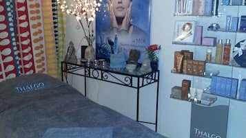 Relax in a serene spa treatment room with a massage table and Thalgo skincare products on display.