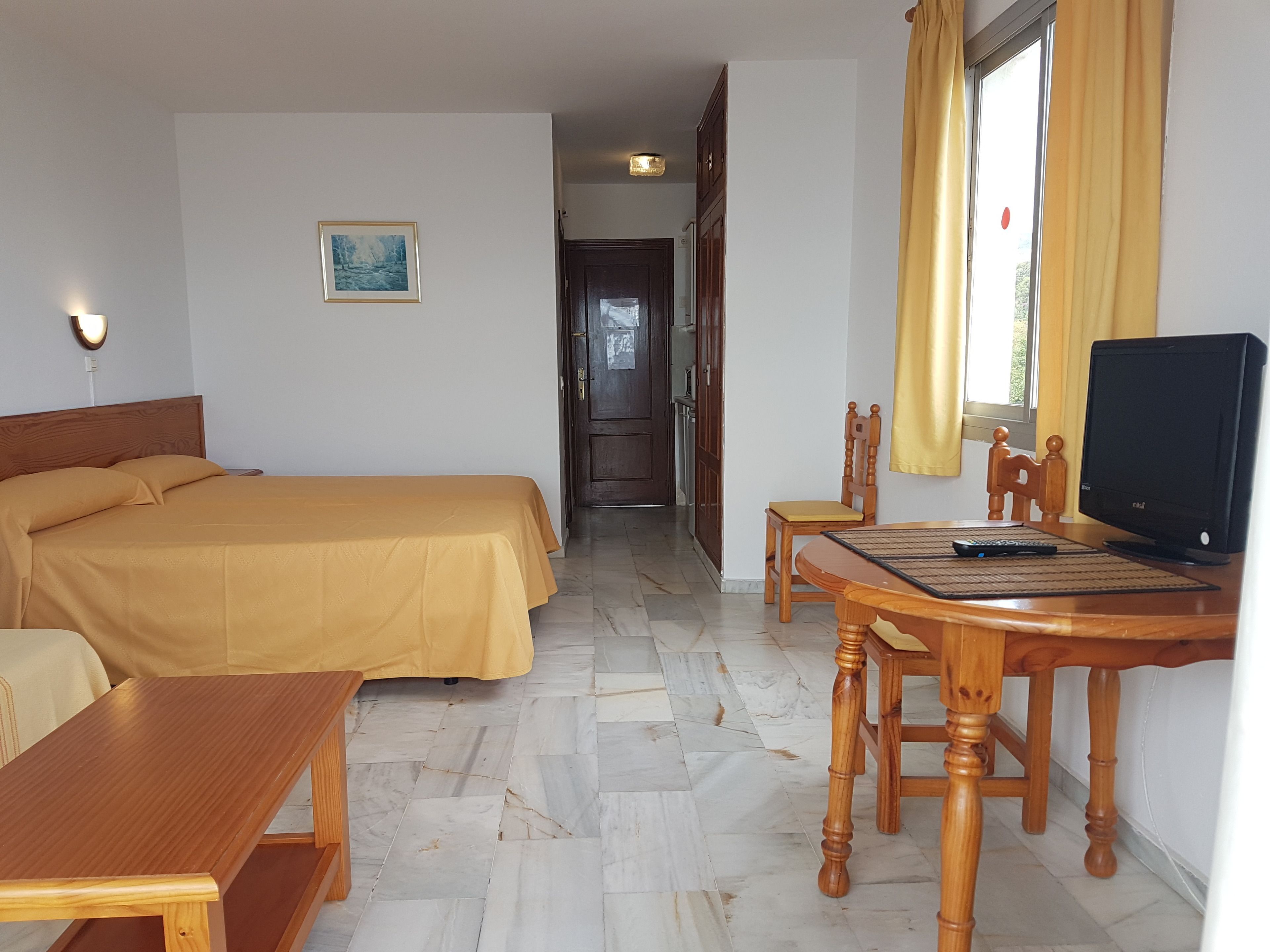 Ein Hotelzimmer mit einem Bett, einem Schreibtisch, einem Sessel, einem Fernseher und einem Bild an der Wand.
