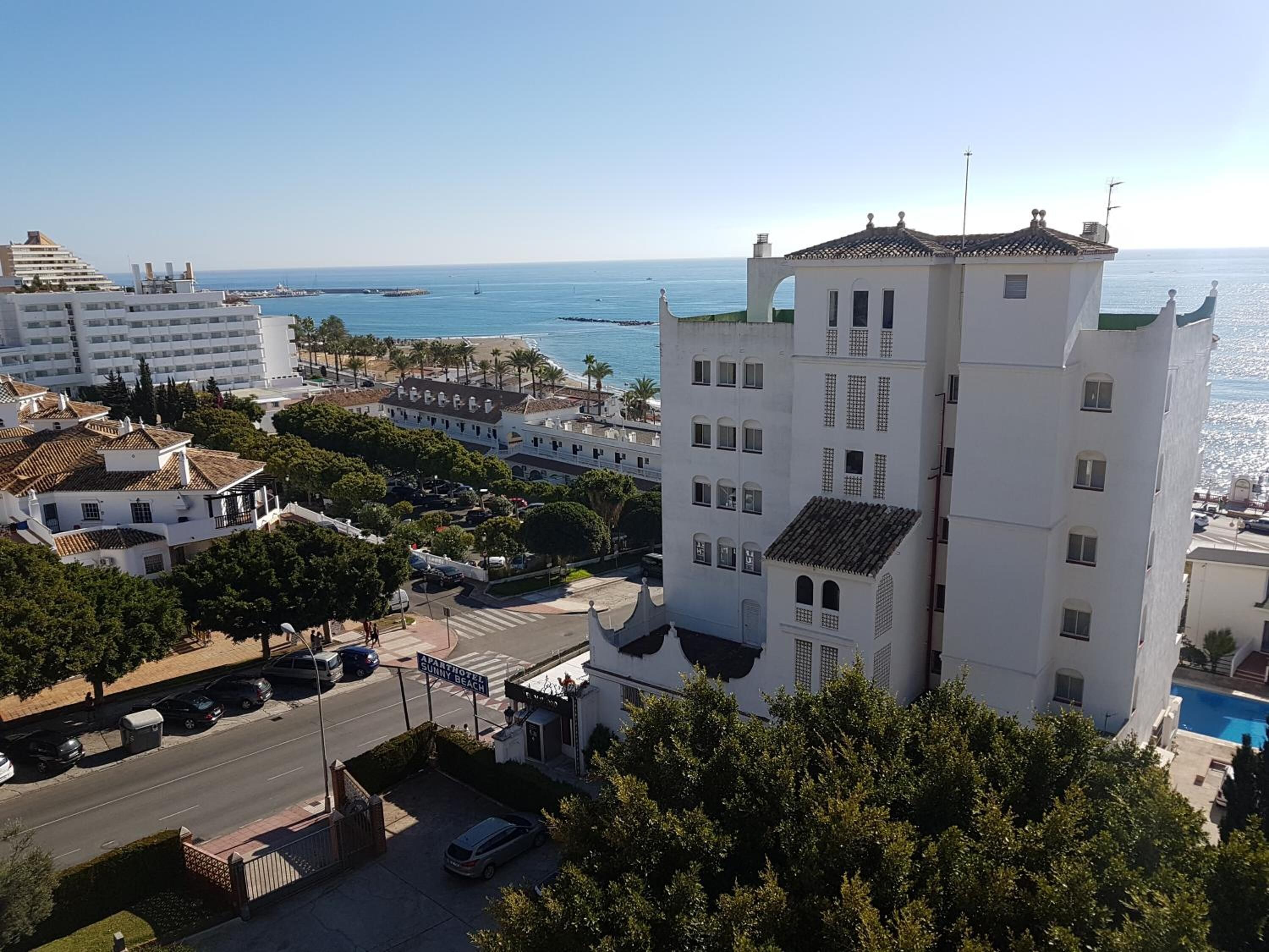 Um hotel à beira-mar com uma torre imponente, piscina e vista para o mar.