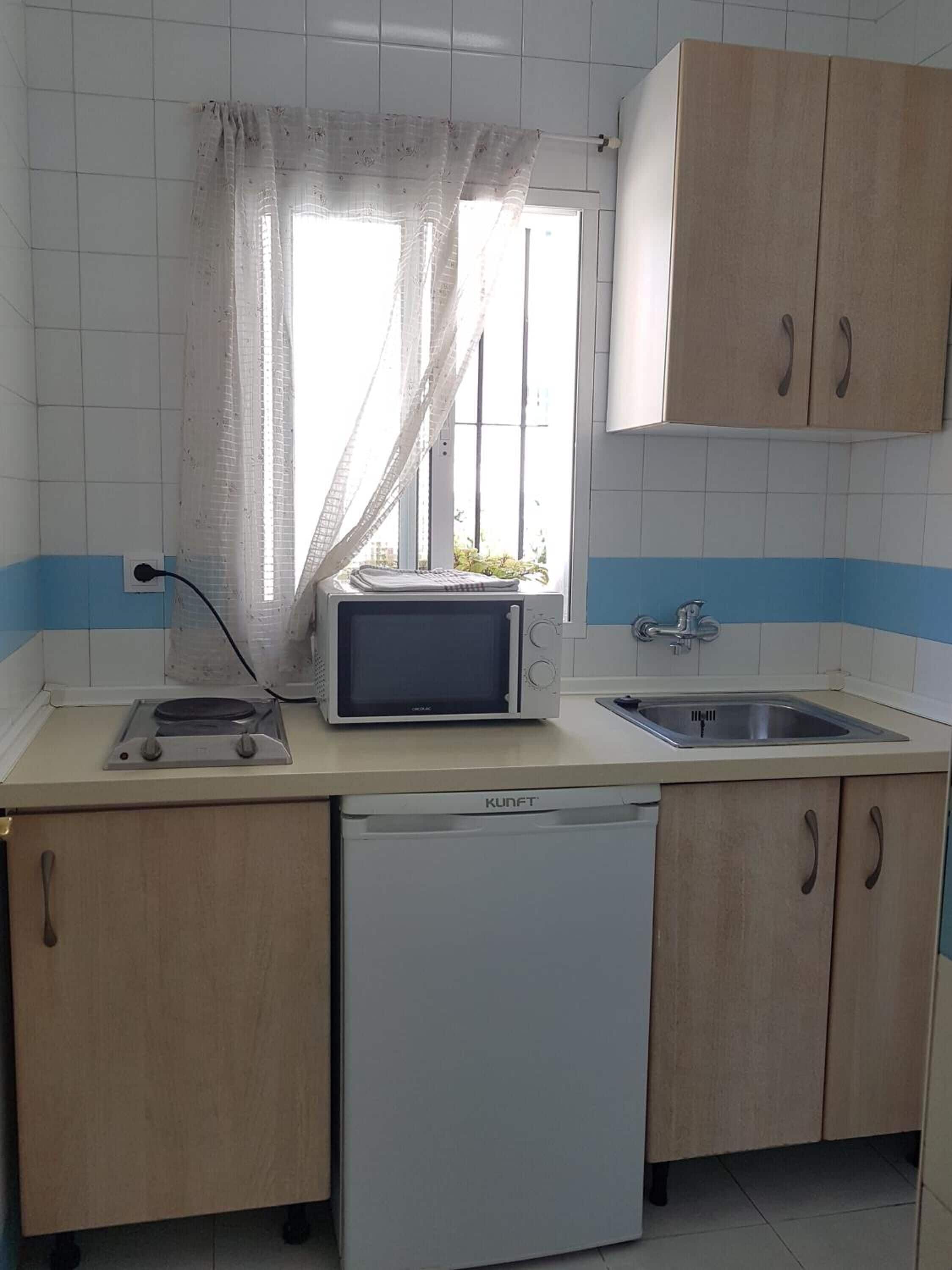 Una cocina compacta equipada con microondas, lavaplatos y pileta.