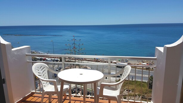 Un balcon avec une table et des chaises donnant sur une vue panoramique de la côte.