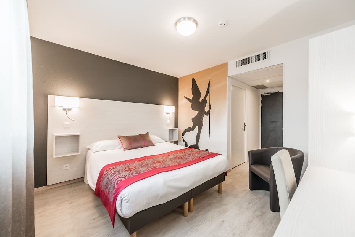 Una habitació d'hotel moderna amb un llit gran, una nit, una cadira i una obra d'art penjada a la paret.