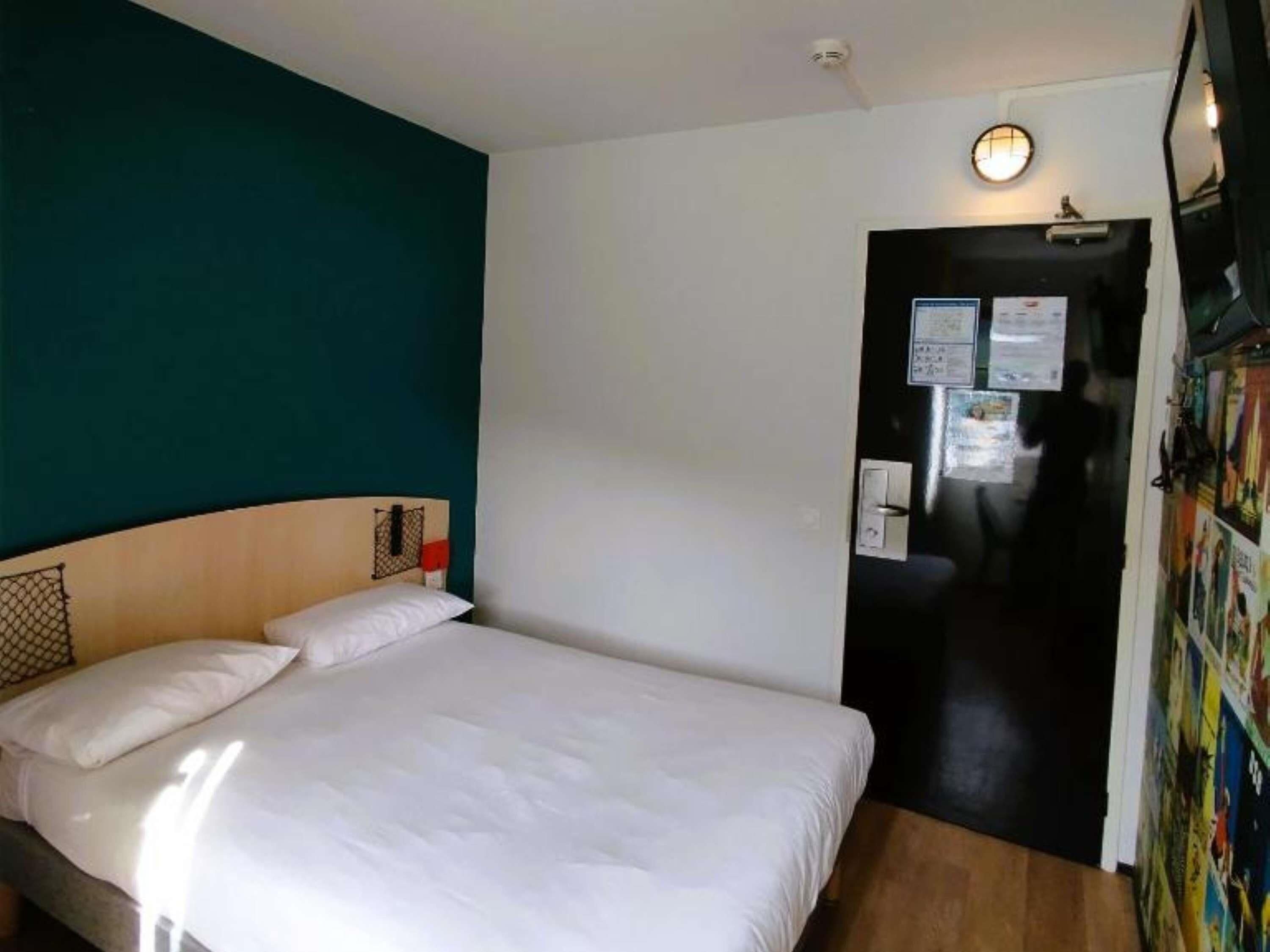 Una habitación con una cama, una puerta y una pared con un cartel.