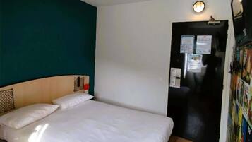 Una habitación con una cama, una puerta y una pared con un cartel.