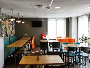 A restaurant with booths, tables, and chairs, a fire exit sign, and a wall with posters.