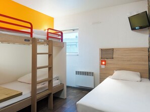 Habitación tipo dormitorio con literas, escritorio, televisor y ventana.