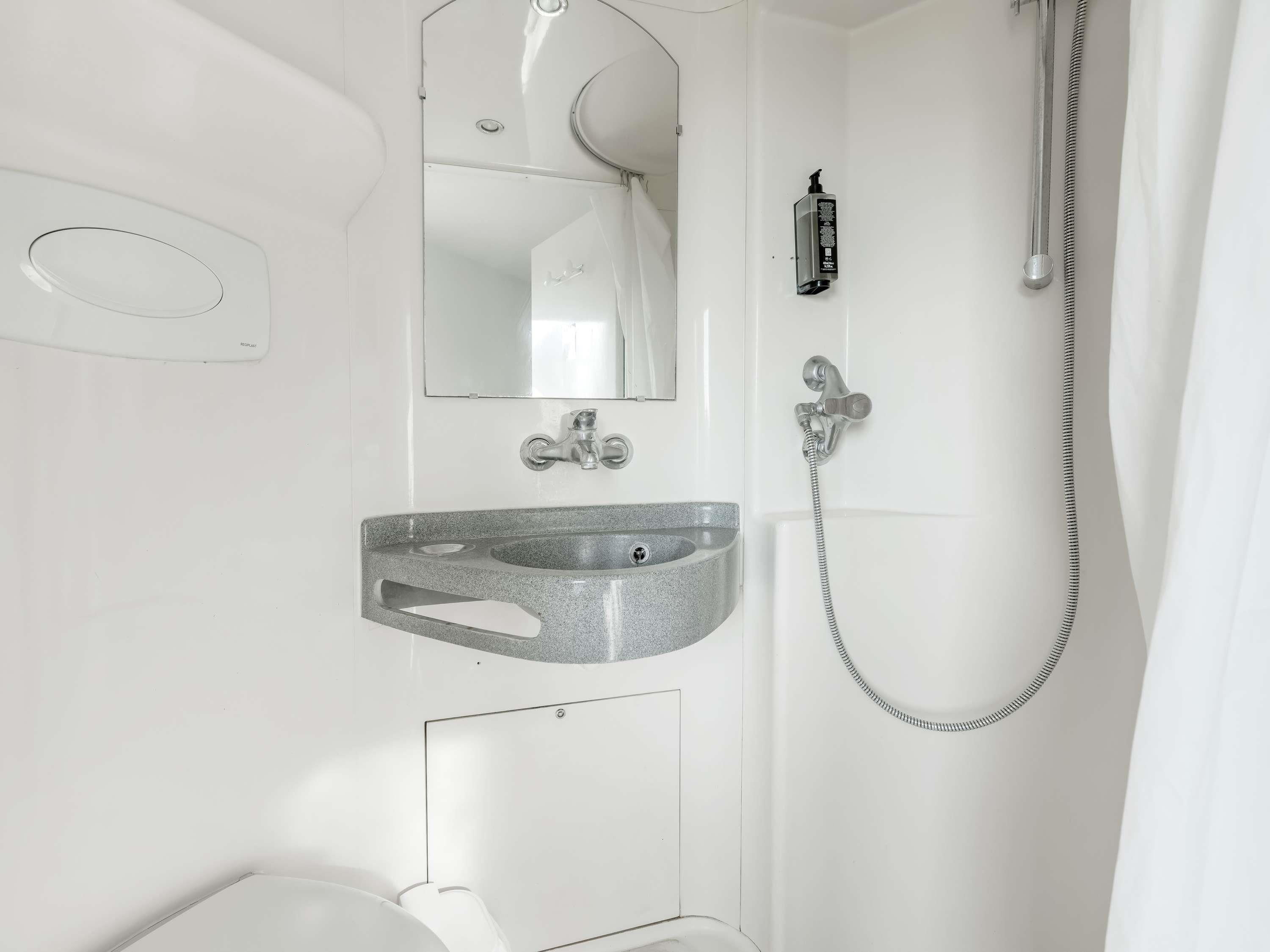 Een badkamer met een wastafel, spiegel en douche.