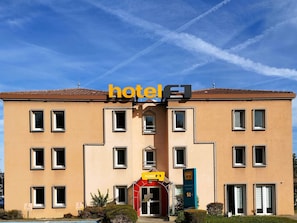 Un edificio de hotel con cielo despejado, un cartel que dice 'hotel' y un cartel de precio que indica '50€'.