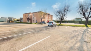 A parking lot with a building that has a sign indicating a hotel. There are cars parked, and the sky is clear. - hotelF1 Lyon Bourgoin-Jallieu (L'Isle-d'Abeau)