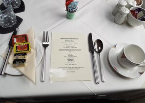 Une table mise pour le petit-déjeuner, avec un menu, des couverts et des condiments.