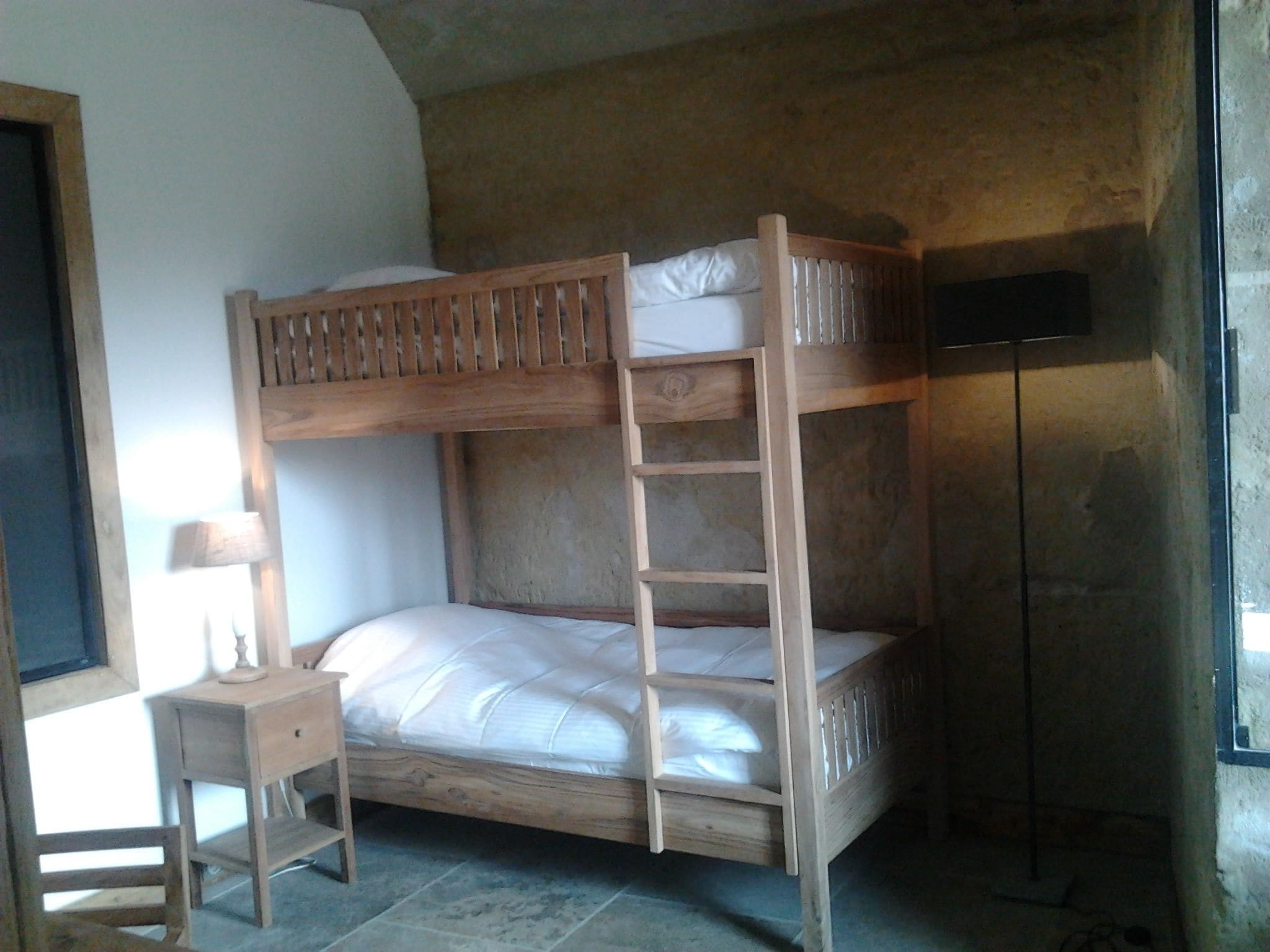 A bunk bed with a ladder, a small bedside table, and a lamp.