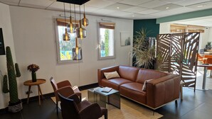 Una sala de estar moderna con un sofá de cuero, una mesa de centro y un comedor con sillas anaranjadas.
