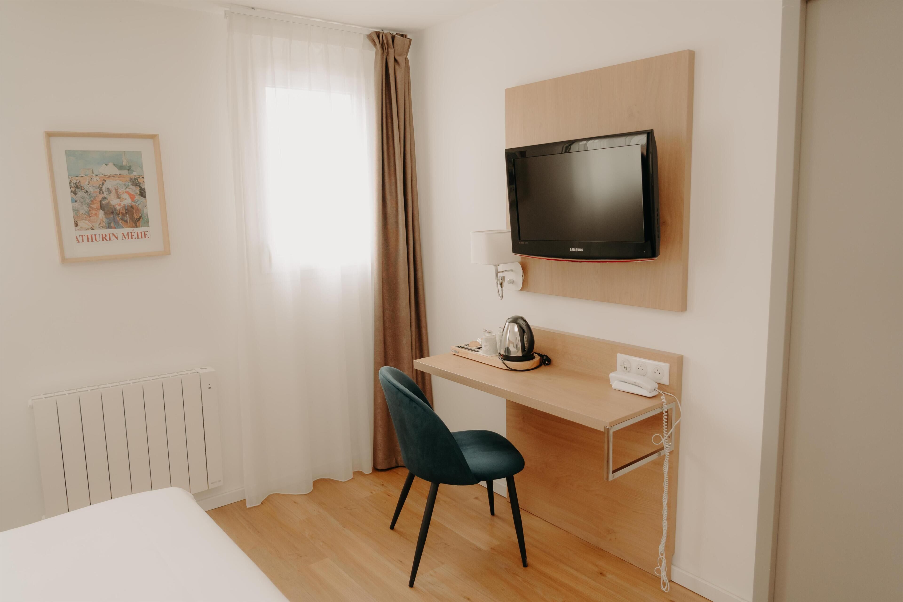 Et hotelværelse med en seng, et skrivebord med stol, et fjernsyn og en radiator.
