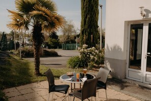 A patio with a round table, two chairs, a glass of orange juice, and a glass of beer. - Hôtel Kyriad Quimper Sud (Quimper)