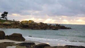 Una costa rocosa con grandes rocas y un faro al fondo.