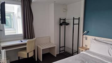 Une chambre d’hôtel équipée d’un lit, d’un bureau, d’une chaise et d’un porte-manteau.