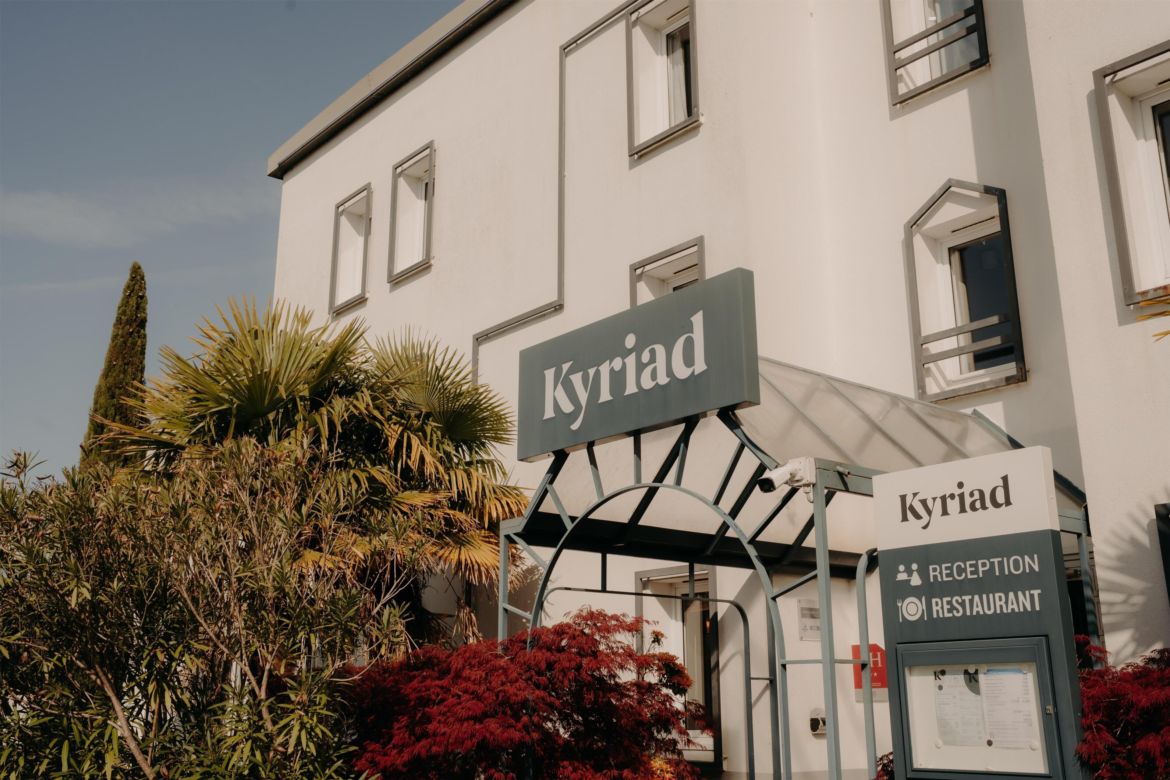 A building with a sign reading 'Kyriad' and a reception area.