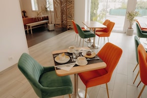 A dining area with a table set for two, chairs, and a bench in the background.