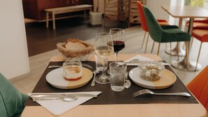 Una mesa de comedor con platos, vasos y cubiertos, en un interior moderno con asientos y vistas.