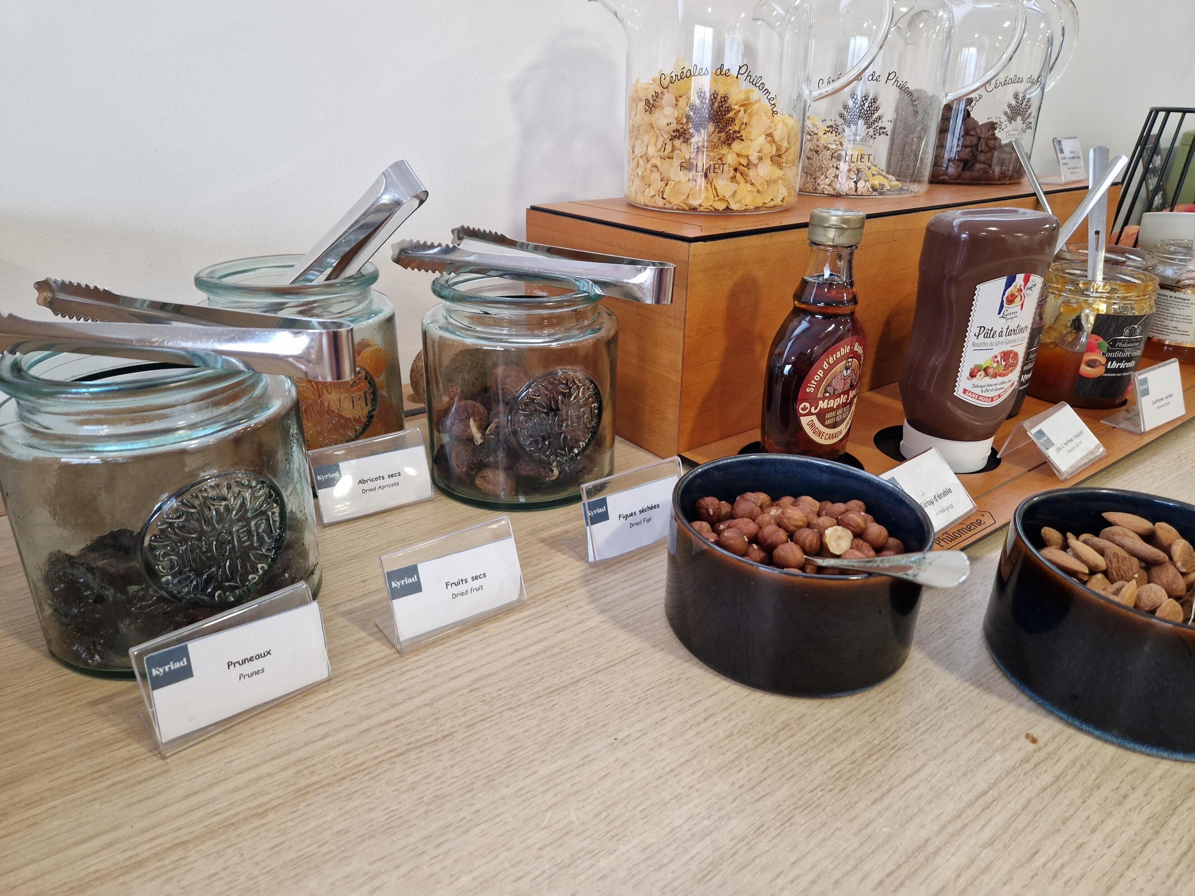 Exhibición de frutos secos y nueces variados con etiquetas, incluyendo ciruelas pasas, albaricoques deshidratados e higos.