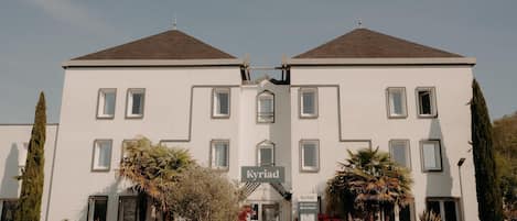 A symmetrical building with a central entrance, two symmetrical wings, and a sign indicating it is a restaurant.