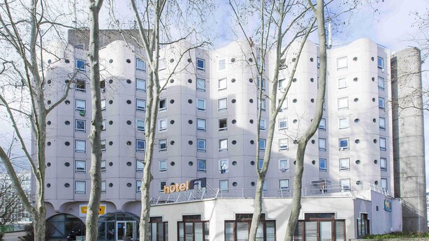 A modern hotel with a unique architectural design, featuring multiple balconies and a central entrance.
